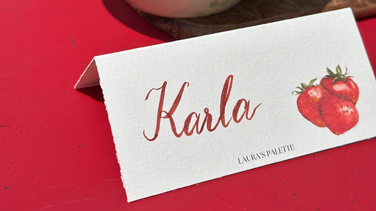 Bowl of blueberries on a red surface with a name card labeled 'Karla' from 'Laura's Palette'.